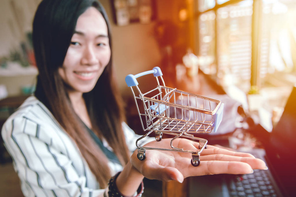 Бизнес-девушка улыбается с картой для покупок в руке для концепции онлайн покупки и продажи
. - Фото, изображение