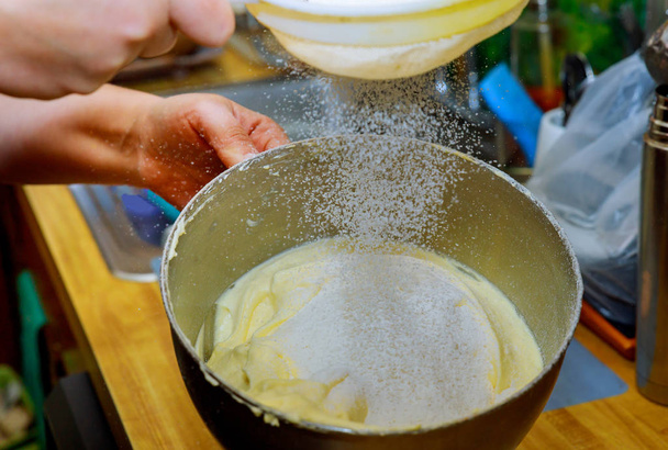 Жінка просіює борошно в мисці міксера, витираючи яйця. Виготовлення тіста для торта
. - Фото, зображення