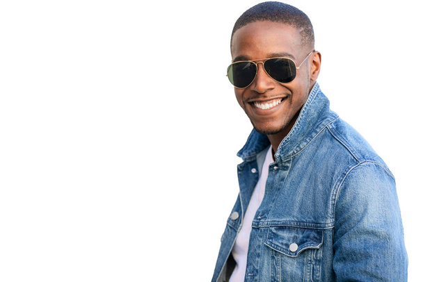 Africký americký komerční model, usměvavý ve stylovém neformálním oblečení, nosí sluneční brýle a džíny, izolovaný na bílém pozadí - Fotografie, Obrázek