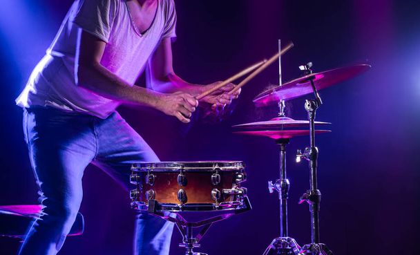 Een drummer drumt op een blauwe achtergrond. Prachtig speciaal effekt - Foto, afbeelding