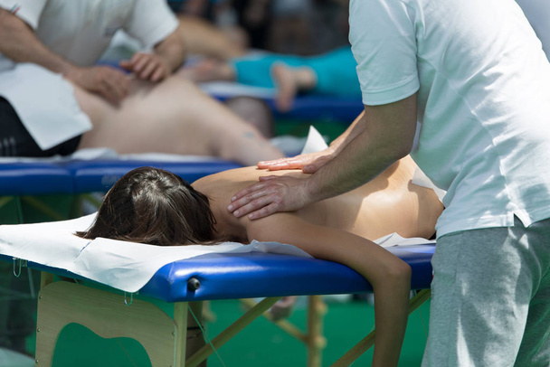 Профессиональный массаж плеч спортсмена на кровати после занятий спортом
 - Фото, изображение