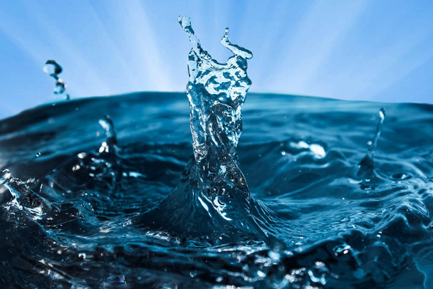 Splash van water close-up tegen de blauwe lucht met stralen. Kroon van bl - Foto, afbeelding