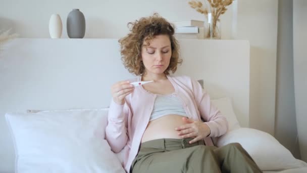 Pregnant Woman Reading Temperature On Thermometer On Bed At Home - Filmati, video