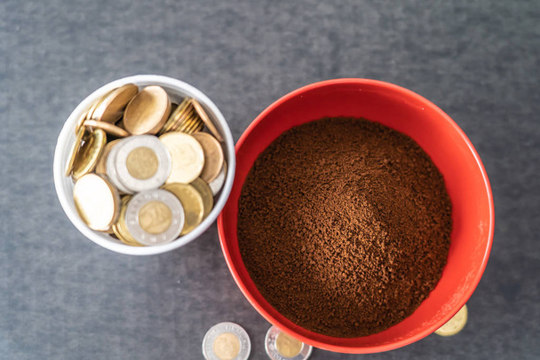 Tazza di polistirolo piena di monete con ciotola rossa di caffè istantaneo
 - Foto, immagini