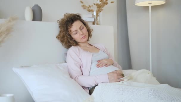 Joven mujer embarazada molesta sintiéndose mal en la cama
 - Metraje, vídeo