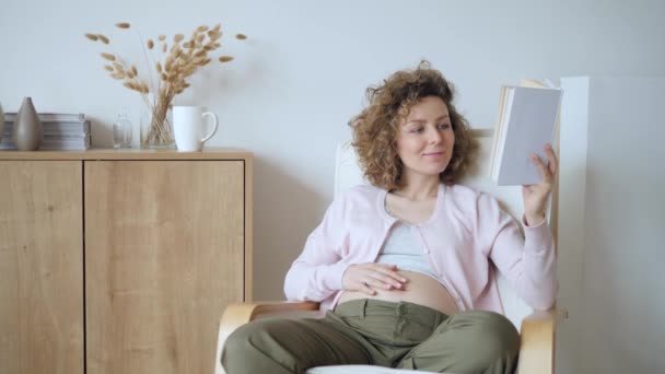 Pregnant Girl Reading A Book At Home - Materiał filmowy, wideo