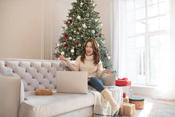 Dark-haired woman near christmas tree having a video call - Foto, afbeelding