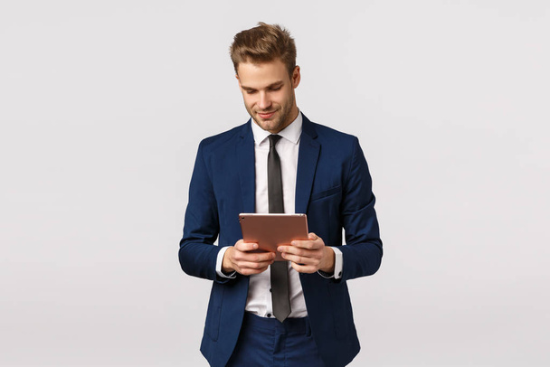 Корпоративная, деловая и финансовая концепция. Красивый уверенный и элегантный молодой бородатый блондин, мужчина-предприниматель постоянный офис, работа, проведение цифровой планшет, стоя на белом фоне
 - Фото, изображение