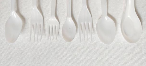 Λευκό πλαστικό κουτάλι και πιρούνι σε λευκό φόντο. - Φωτογραφία, εικόνα