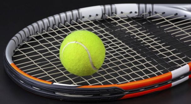 tennisracket en bal op zwarte achtergrond - Foto, afbeelding