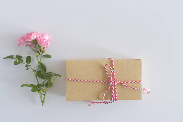 Top view of a beautiful small pink rose and gift box on a white table. Flat lay, top view. Romance and love card.Christmas concept. - Foto, afbeelding