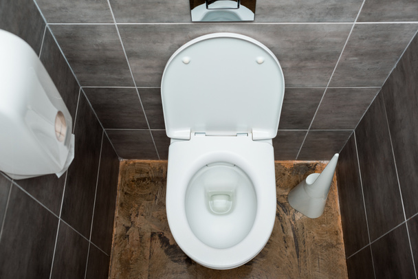 керамическая чистая унитаз в современном туалете с серой плиткой и туалетной щеткой
 - Фото, изображение