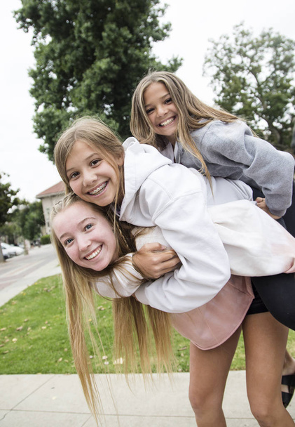 Három tini lányból álló csoport, akik jól érzik magukat és együtt játszanak a szabadban. Aranyos tizenéves lányok hátat fordítanak egymásnak. - Fotó, kép