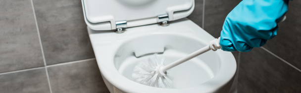 vista cortada de limpeza lavatório cerâmico vaso sanitário com escova de vaso sanitário em banheiro moderno com azulejo cinza, tiro panorâmico
 - Foto, Imagem