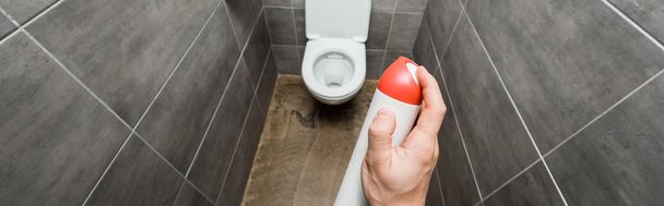 обрізаний вид людини, що розбризкує освіжувач повітря в сучасному туалеті з сірою плиткою
 - Фото, зображення