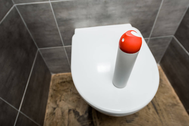 air freshener in spray bottle on ceramic clean toilet bowl in modern restroom with grey tile - Foto, afbeelding