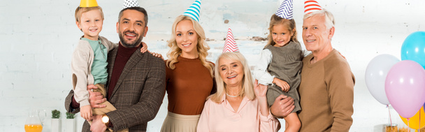plano panorámico de familia feliz posando en la cámara en gorras de fiesta
 - Foto, Imagen