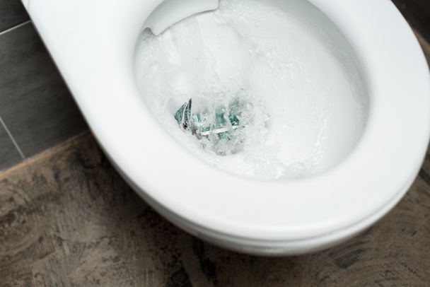 czysta biała muszla klozetowa z spłukiwaniem pieniędzy w nowoczesnej toalecie z szarą płytką - Zdjęcie, obraz