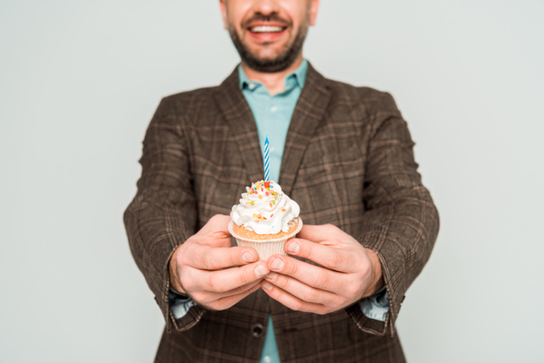 recortado vista de sonriente hombre celebración cumpleaños cupcake aislado en gris
 - Foto, Imagen