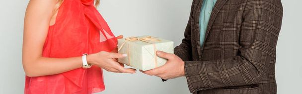 cropped view of man presenting gift box to wife isolated on grey, panoramic shot - Фото, изображение