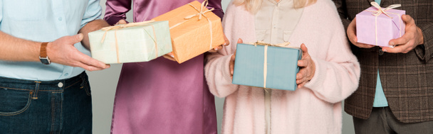 przycięty widok starszych rodziców z dorosłym synem i córką trzymających pudełka prezentów odizolowane na szarym, panoramicznym ujęciu - Zdjęcie, obraz