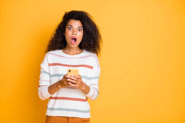 It is unbelievable. Photo of terrified girl checking testing new model of telephone expressing shock on her face isolated bright color background - 写真・画像