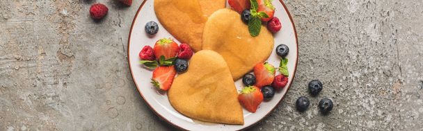 top view of heart shaped pancakes with berries on grey concrete surface, panoramic shot - Photo, Image