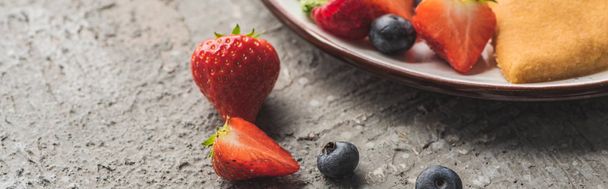 close up view of fresh berries near delicious heart shaped pancakes on grey concrete surface, panoramic shot - Photo, Image
