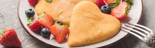 close up view of delicious heart shaped pancakes with berries on plate with fork, panoramic shot - Photo, Image
