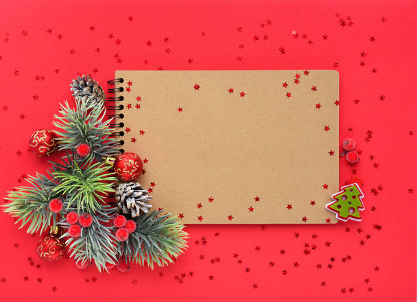 Composición navideña. El cuaderno y las ramas de abeto sobre fondo rojo
 - Foto, Imagen
