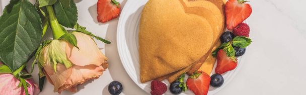 top view of delicious heart shaped pancakes with berries near roses on white background, panoramic shot - Φωτογραφία, εικόνα