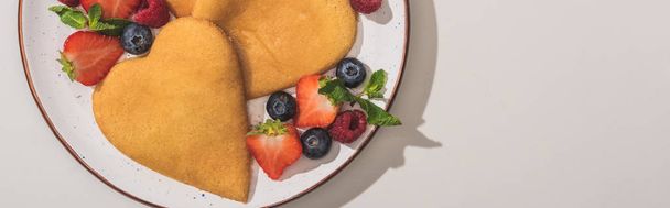 top view of tasty heart shaped pancakes with berries and mint on white background, panoramic shot - Foto, immagini