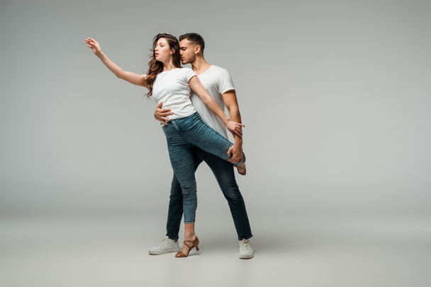 танцюристи в футболках і джинсах танцюють баната на сірому фоні
  - Фото, зображення