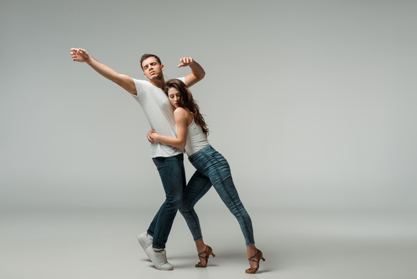 dancers in denim jeans dancing bachata on grey background  - Photo, image