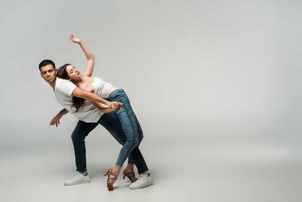 dancers with closed eyes dancing bachata on grey background  - Foto, afbeelding