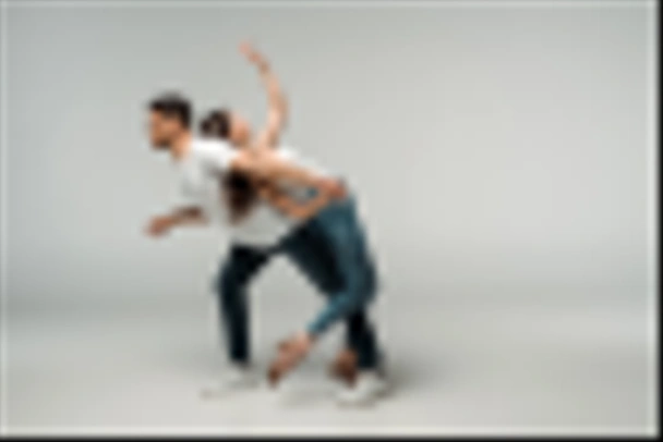 side view of dancers in denim jeans dancing bachata on grey background  - 写真・画像