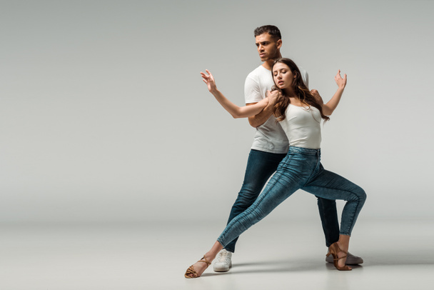 dancers in denim jeans dancing bachata on grey background  - Photo, Image