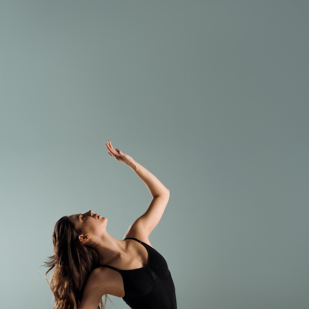 attractive dancer in black bodysuit dancing contemporary isolated on grey   - Zdjęcie, obraz