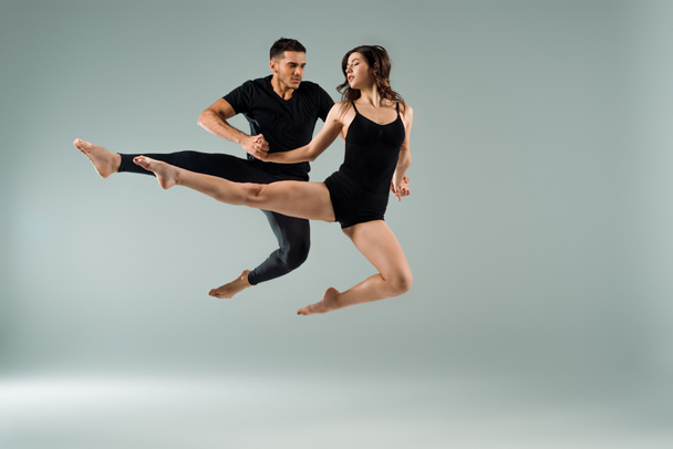 handsome and attractive dancers dancing contemporary on grey background  - Foto, afbeelding