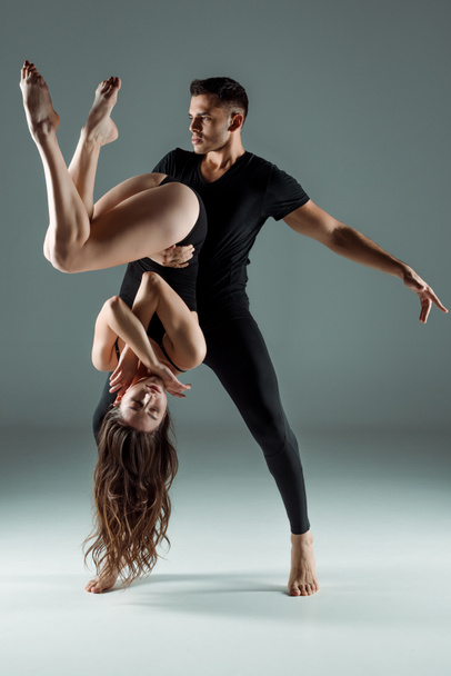handsome and attractive dancers dancing contemporary on dark background  - Фото, изображение