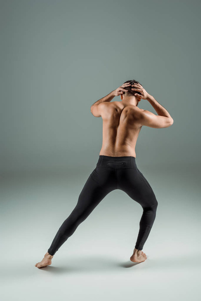 back view of dancer in black leggings dancing contemporary on dark background - Fotoğraf, Görsel