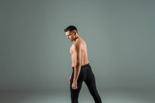 handsome dancer in black leggings dancing contemporary on grey background - Foto, imagen
