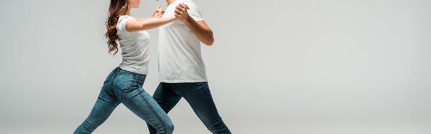 panoramic shot of dancers in t-shirts and jeans dancing bachata isolated on grey  - Fotoğraf, Görsel
