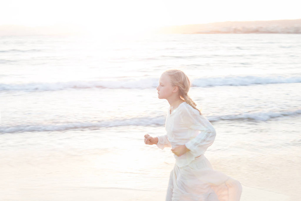 Блондинка біжить на заході сонця на пляжі Європи. - Фото, зображення