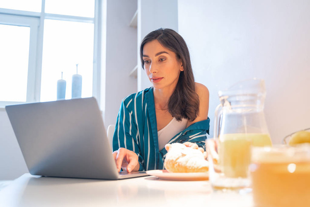 Calm lady looking at the laptop screen at home stock photo - Foto, imagen