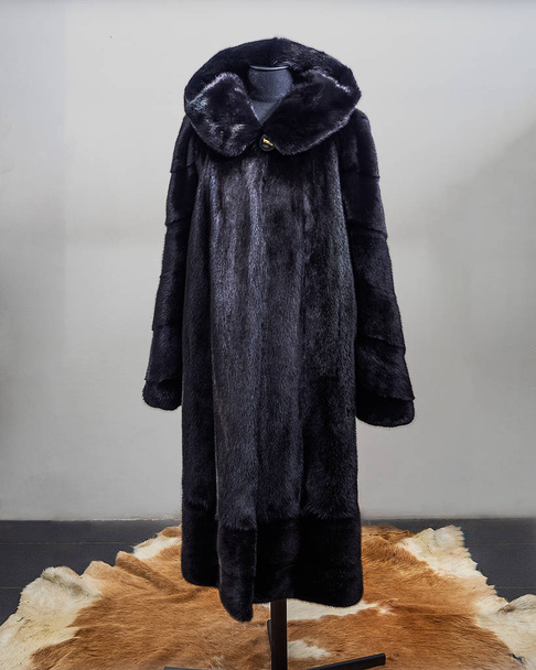 Black mink fur coat loose silhouette with a hood on the construction site of the trading hall - Valokuva, kuva