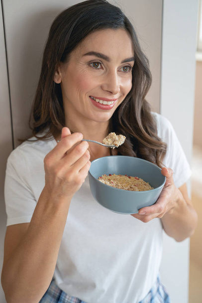 Woman eating favorite porridge for breakfast stock photo - Photo, image