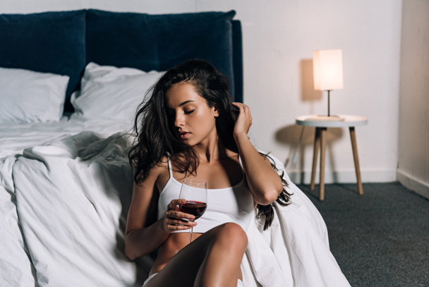 sexy, ragazza sognante in possesso di un bicchiere di vino rosso mentre seduto sul pavimento in camera da letto
 - Foto, immagini