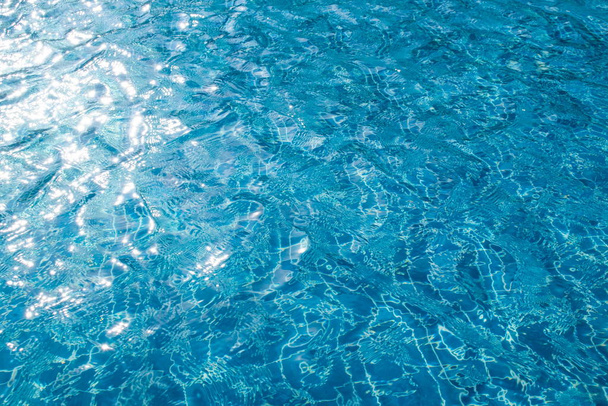 Αφηρημένη εικόνα φως του ήλιου αντανακλάται στην επιφάνεια του μπλε νερού στην πισίνα. (Επιλεκτική εστίαση) - Φωτογραφία, εικόνα