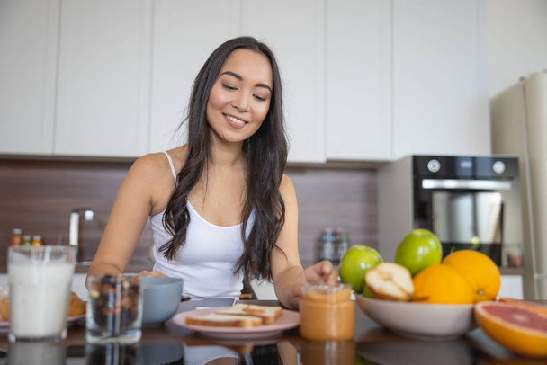 Young woman having breakfast in the kitchen - Photo, image